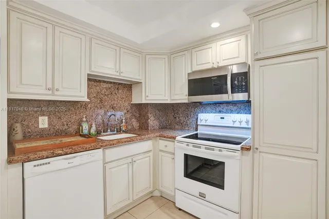 a kitchen with white cabinets and white appliances