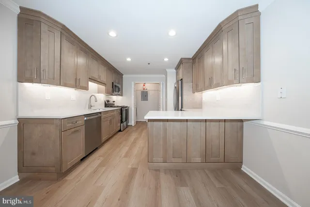 an empty room with wooden floor cabinet and windows