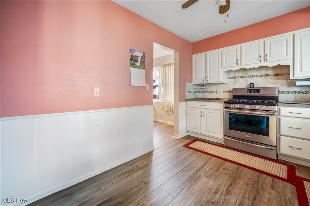 844 Roseland Road Alliance, OH 44601 - Photo 21 of 40 Kitchen with white cabinetry, hardwood / wood-style flooring, gas stove, and decorative backsplash