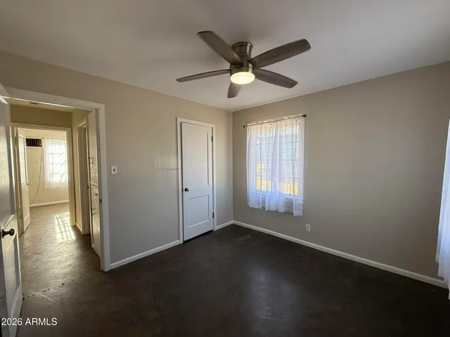 an empty room with wooden floor fan and windows