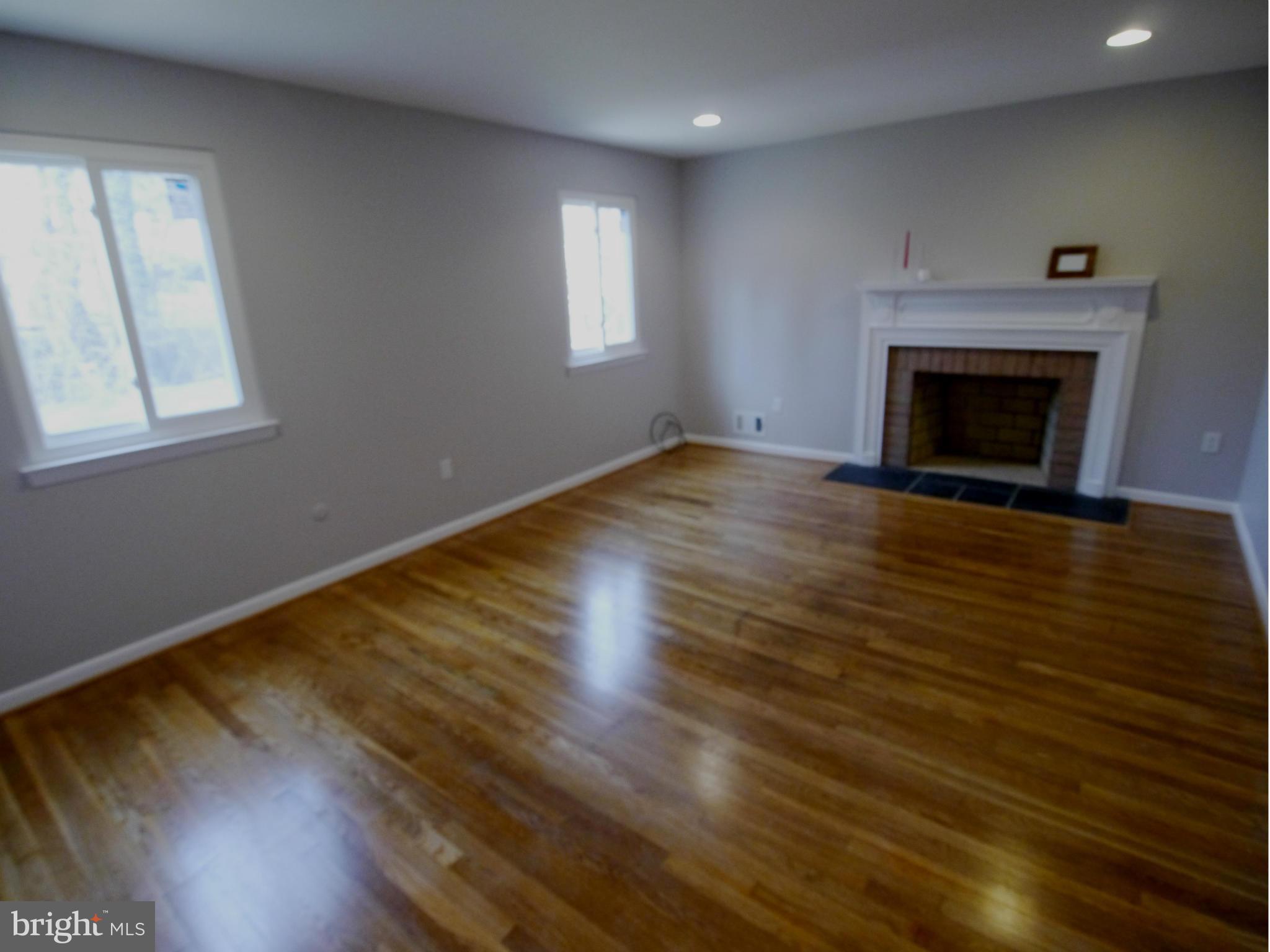 13100 Middlevale Lane Silver Spring, MD 20906 - Photo 19 of 30 an empty room with wooden floor a fireplace and windows