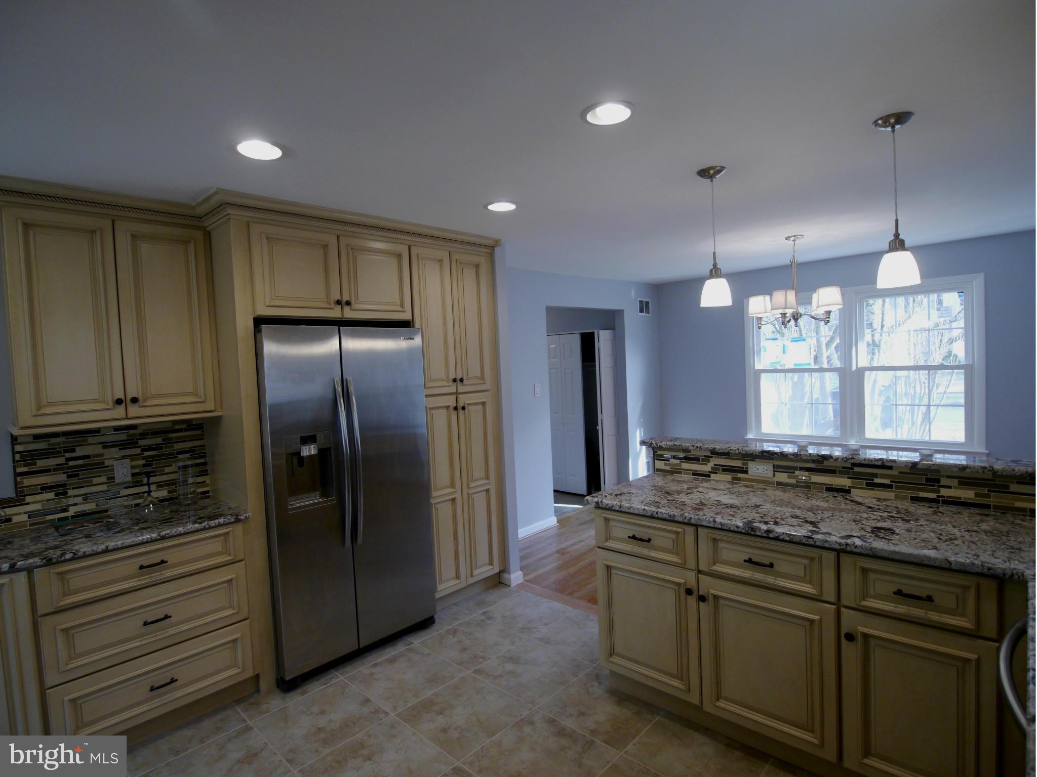 13100 Middlevale Lane Silver Spring, MD 20906 - Photo 7 of 30 a kitchen with kitchen island granite countertop cabinets and refrigerator