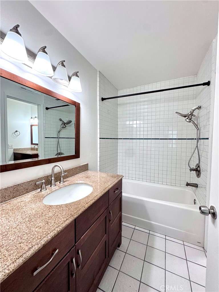 4692 Heil Avenue Huntington Beach, CA 92649 - Photo 10 of 27 a bathroom with a granite countertop sink a mirror and a bathtub with shower