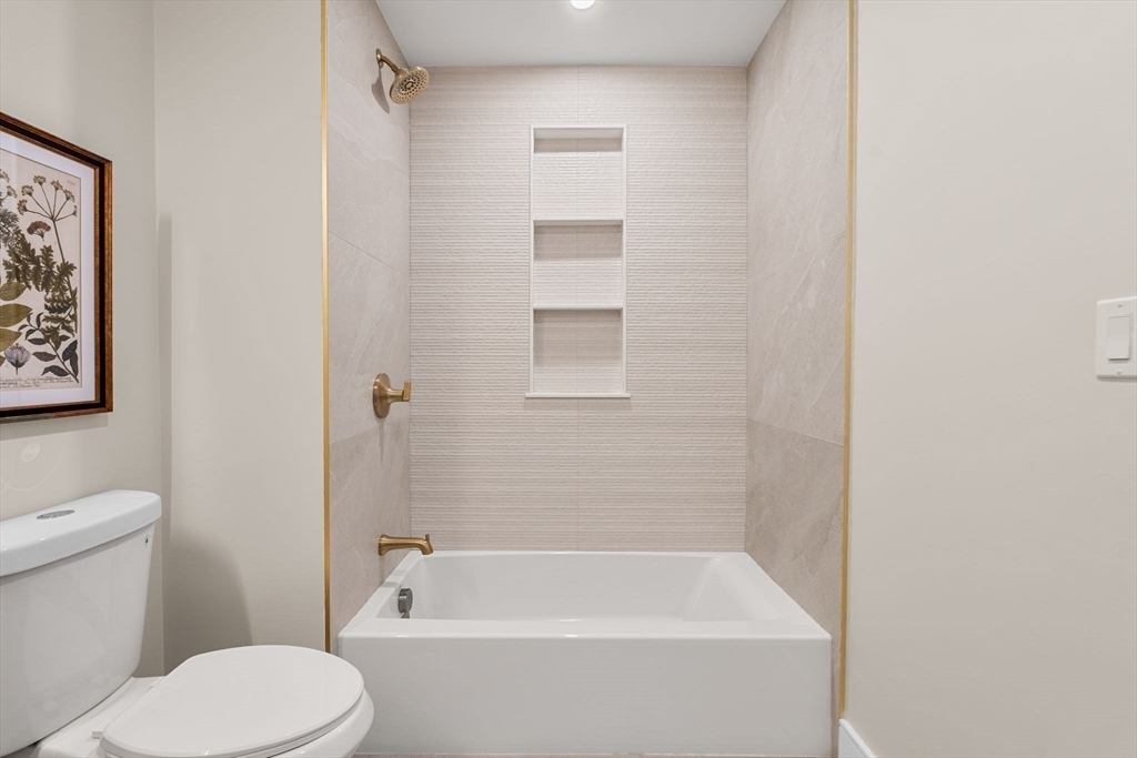 27 Guild Street, Unit 102 Boston, MA 02119 - Photo 23 of 29 a bathroom with a toilet and a bathtub