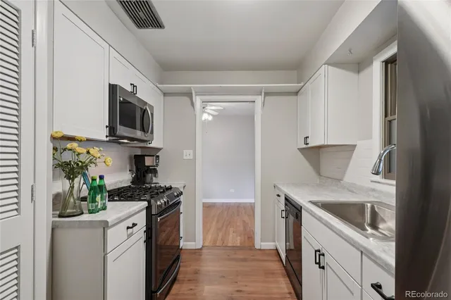 a kitchen with stainless steel appliances a white stove top oven a sink a counter space and cabinets