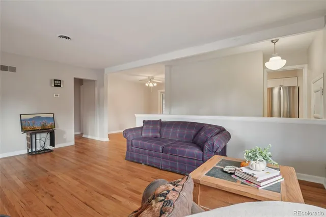 a living room with couches and a dining table with wooden floor