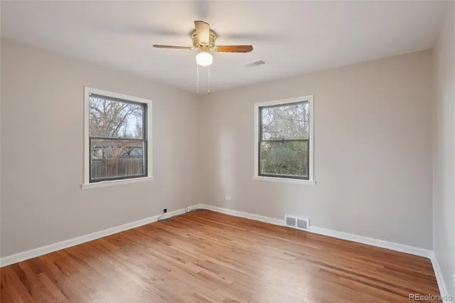 a view of an empty room with window and wooden floor