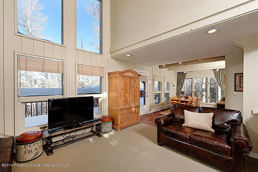 47 North Ridge Lane, Unit B Snowmass Village, CO 81615 - Photo 3 of 18 a living room with furniture a flat screen tv and a floor to ceiling window