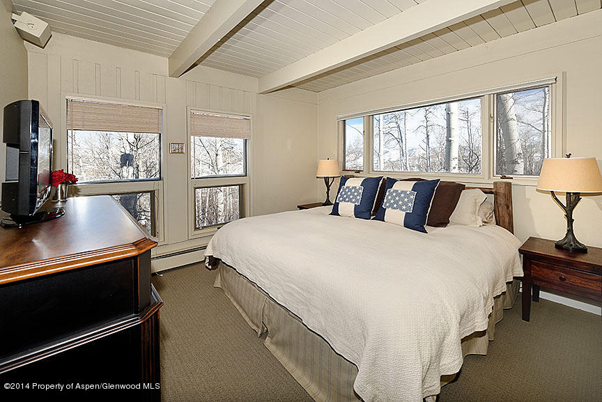 47 North Ridge Lane, Unit B Snowmass Village, CO 81615 - Photo 8 of 18 a bedroom with a bed and a flat tv screen on dresser