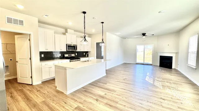 a kitchen with stainless steel appliances kitchen island granite countertop a stove top oven a sink a counter space and cabinets