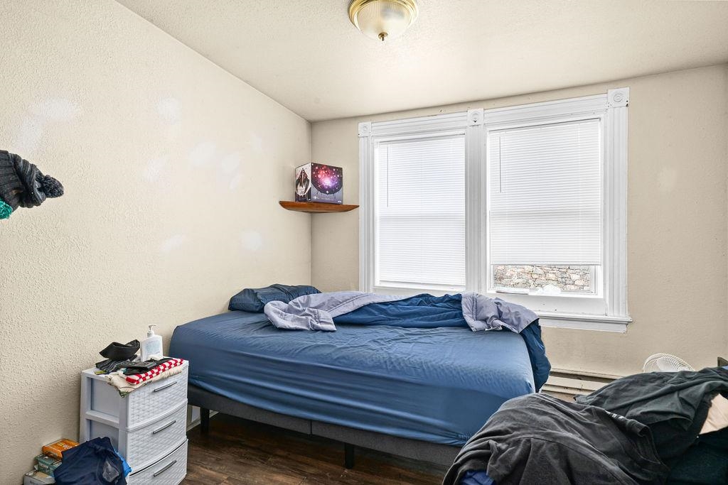 628 West 3rd Street Duluth, MN 55806 - Photo 5 of 8 Bedroom with a textured wall, wood finished floors, and a baseboard radiator
