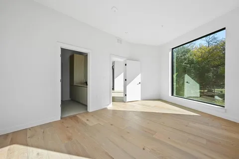 a view of a big room with wooden floor and a large window with outer view