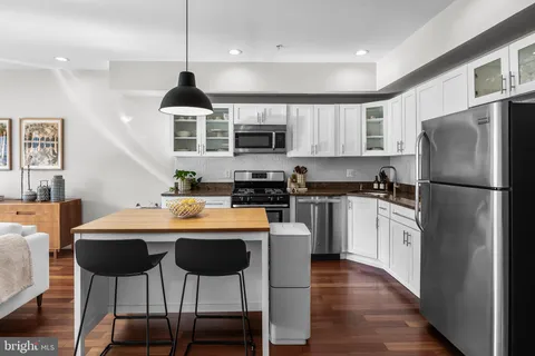 a kitchen with stainless steel appliances granite countertop a refrigerator a stove a sink dishwasher and a refrigerator with wooden floor