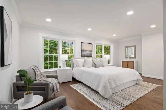 a bedroom with a large bed couch and windows