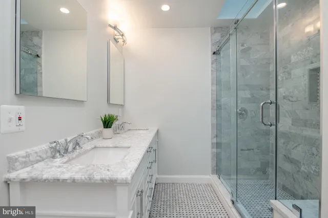 a bathroom with a granite countertop sink a mirror and shower
