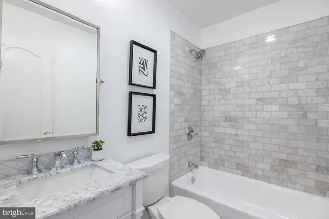 a bathroom with a granite countertop sink a toilet and bathtub