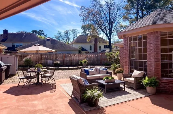 a view of a patio with couches table and chairs with potted plants and a barbeque
