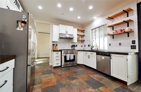 a kitchen with stainless steel appliances granite countertop a stove a sink and a refrigerator