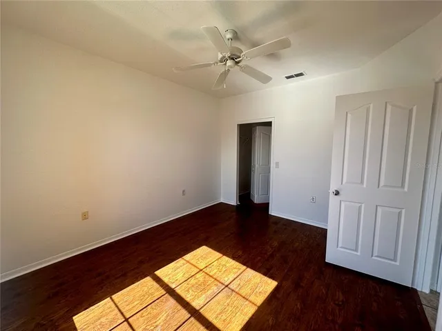 an empty room with wooden floor closet and windows
