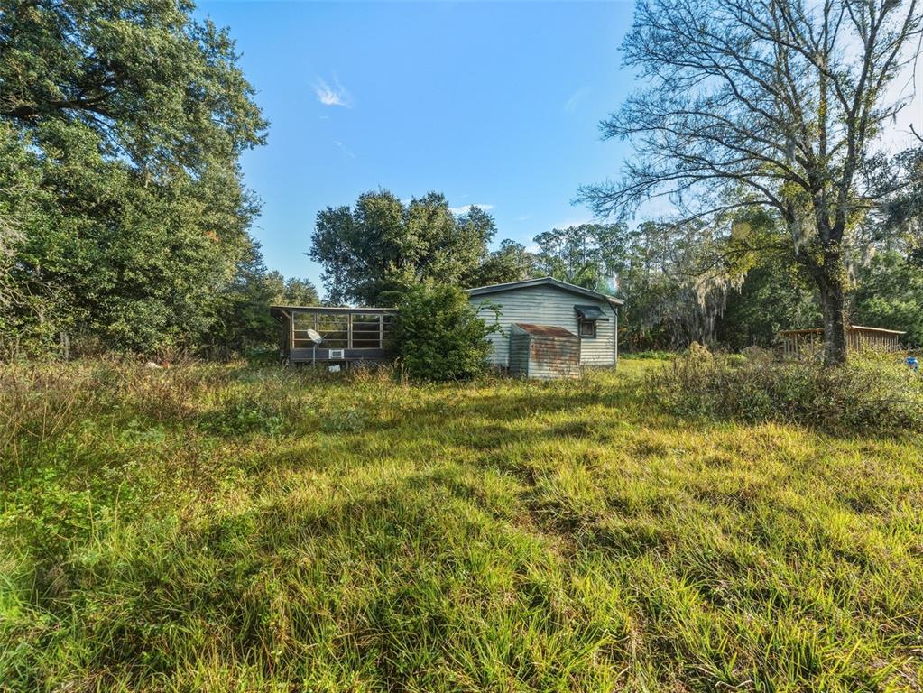 7275 Knowles Road Polk City, FL 33868 - Photo 24 of 39 a backyard of a house with table and chairs under an umbrella