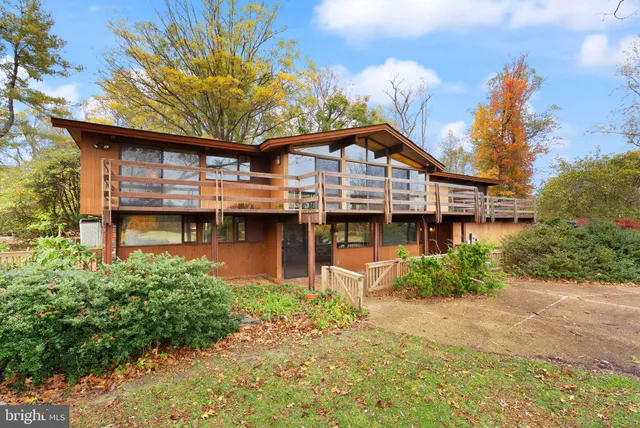 a backyard of a house with large trees and table and chairs