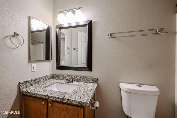 a bathroom with a granite countertop sink and a toilet