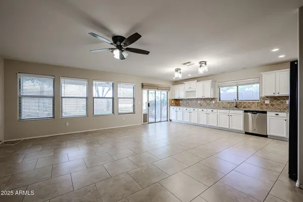 a view of an empty room with kitchen and window