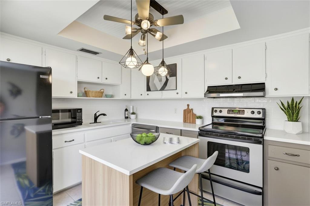 355 Palm Drive, Unit 732 Naples, FL 34112 - Photo 15 of 50 355-Palm-Dr-732-Naples-FL-virtual staged kitchen featuring black appliances, backsplash, open shelves, dual tone cabinets, and a breakfast bar