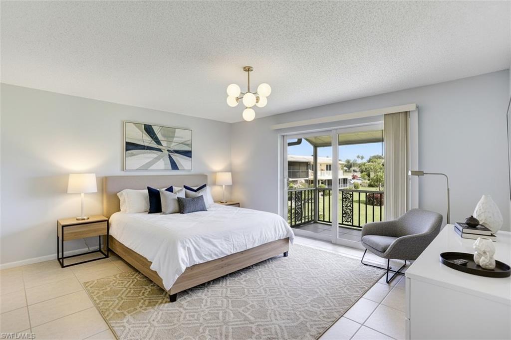 355 Palm Drive, Unit 732 Naples, FL 34112 - Photo 18 of 50 Bedroom - virtual staged - with access to outside, a textured ceiling, light tile patterned floors, and hanging lights