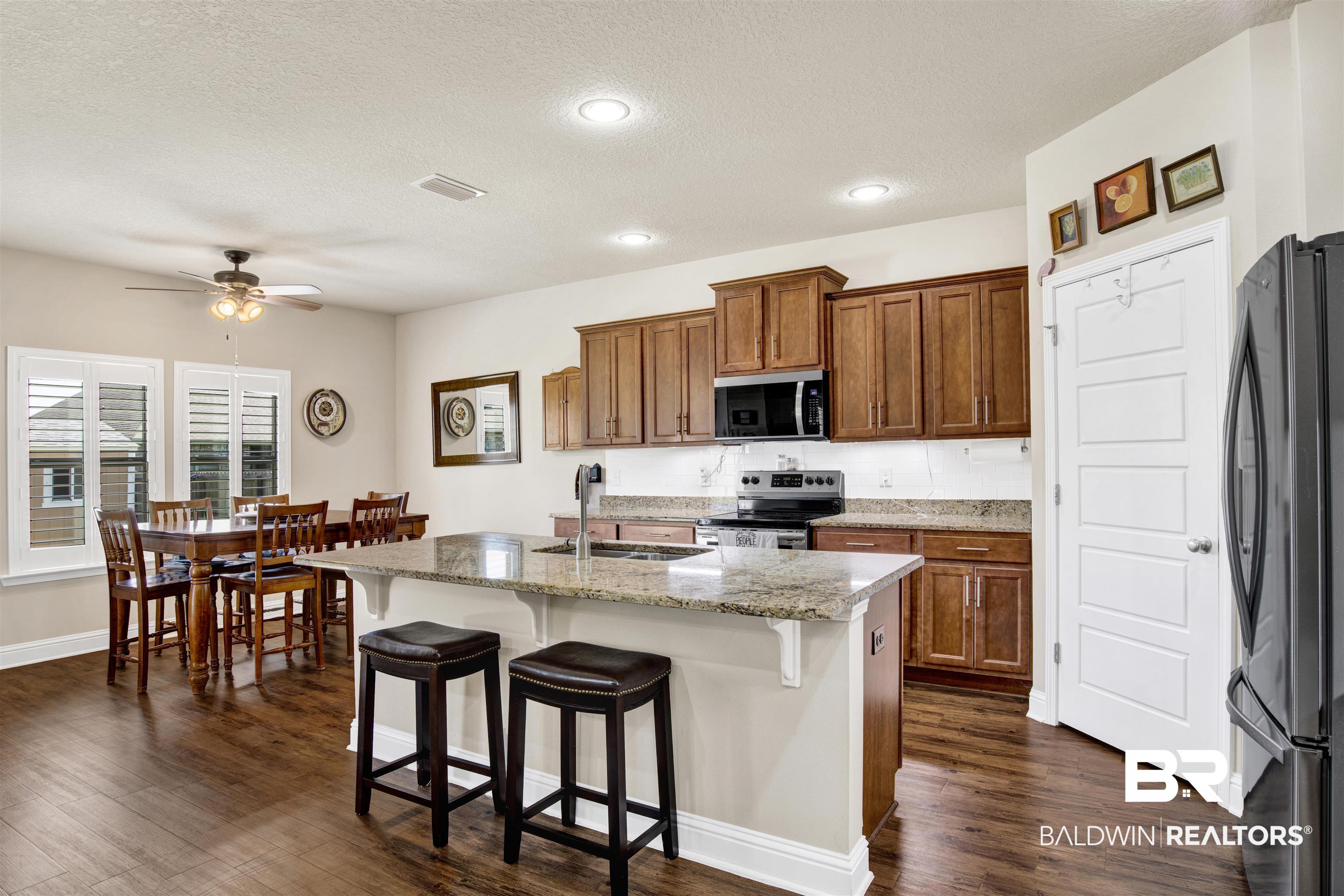 278 Silo Loop Fairhope, AL 36532 - Photo 5 of 26 Kitchen featuring appliances with stainless steel finishes, ceiling fan, dark wood-type flooring, brown cabinetry, and a textured ceiling
