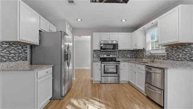 a kitchen with stainless steel appliances a sink stove refrigerator and cabinets