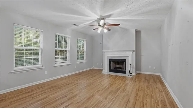 a view of an empty room with wooden floor fireplace and a window
