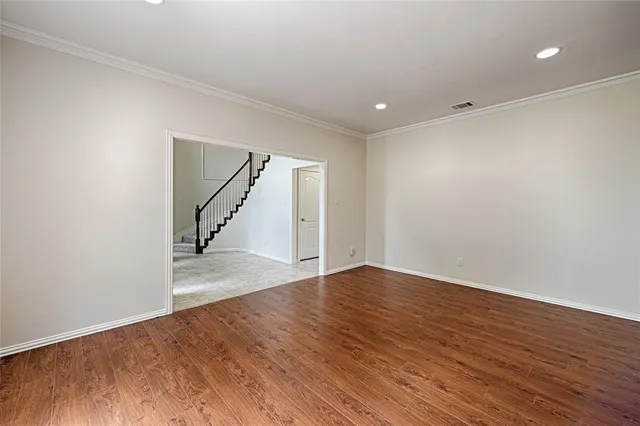 a view of an empty room with wooden floor and stairs