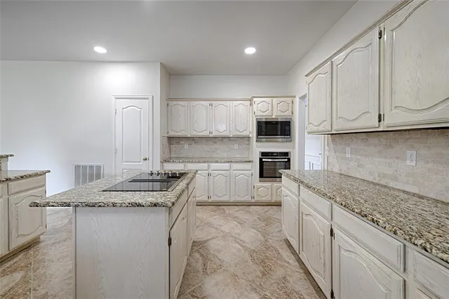 a kitchen with granite countertop a sink stove and cabinets