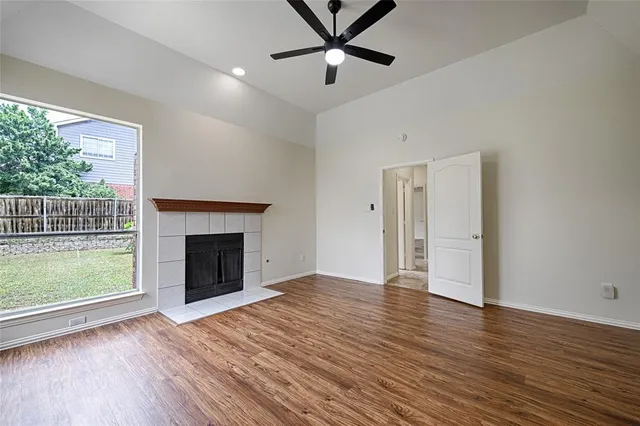an empty room with wooden floor a fireplace and windows