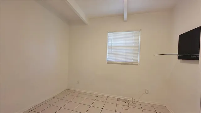 a view of an empty room with wooden floor and a flat screen tv