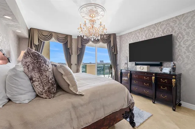 a spacious bedroom with a bed and a flat tv screen on dresser