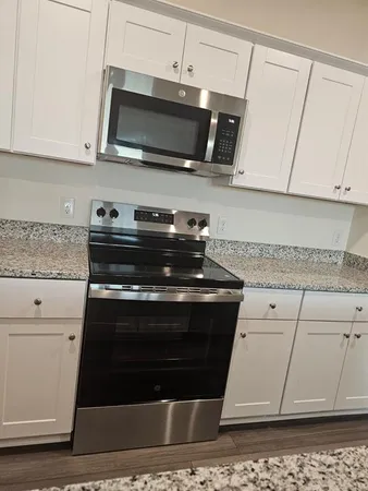 a kitchen with stainless steel appliances granite countertop a stove a microwave and a white cabinets