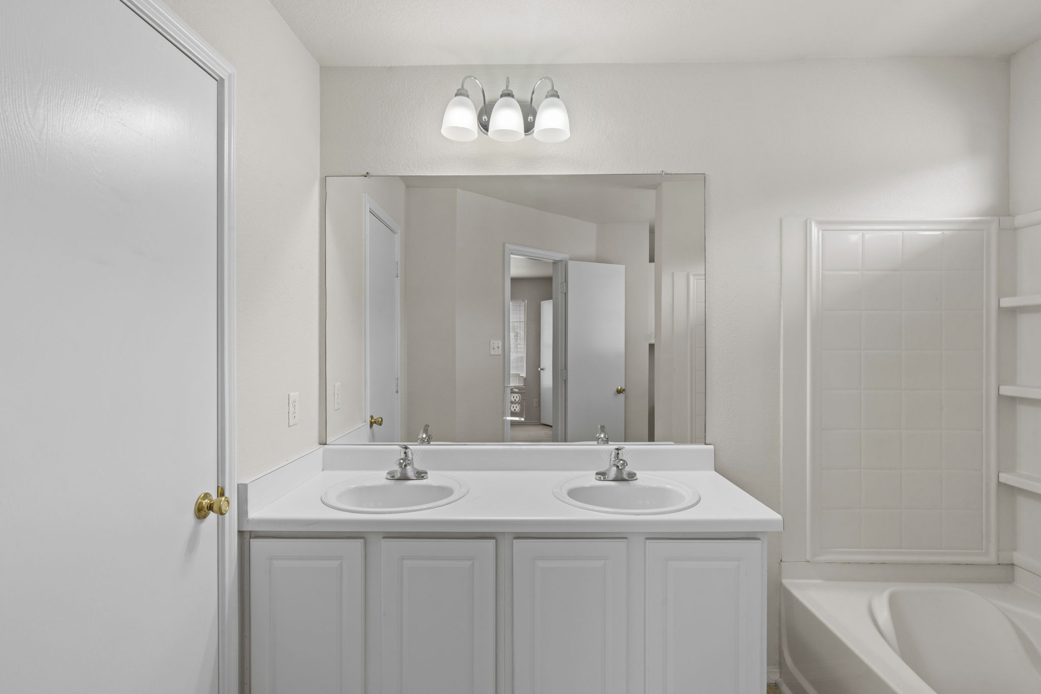 208 Dandelion Loop Kyle, TX 78640 - Photo 24 of 39 Primary bathroom featuring a double vanity with two sinks, a large mirror, and a tiled shower/tub combination