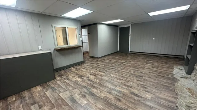 an empty room with wooden floor fireplace and windows
