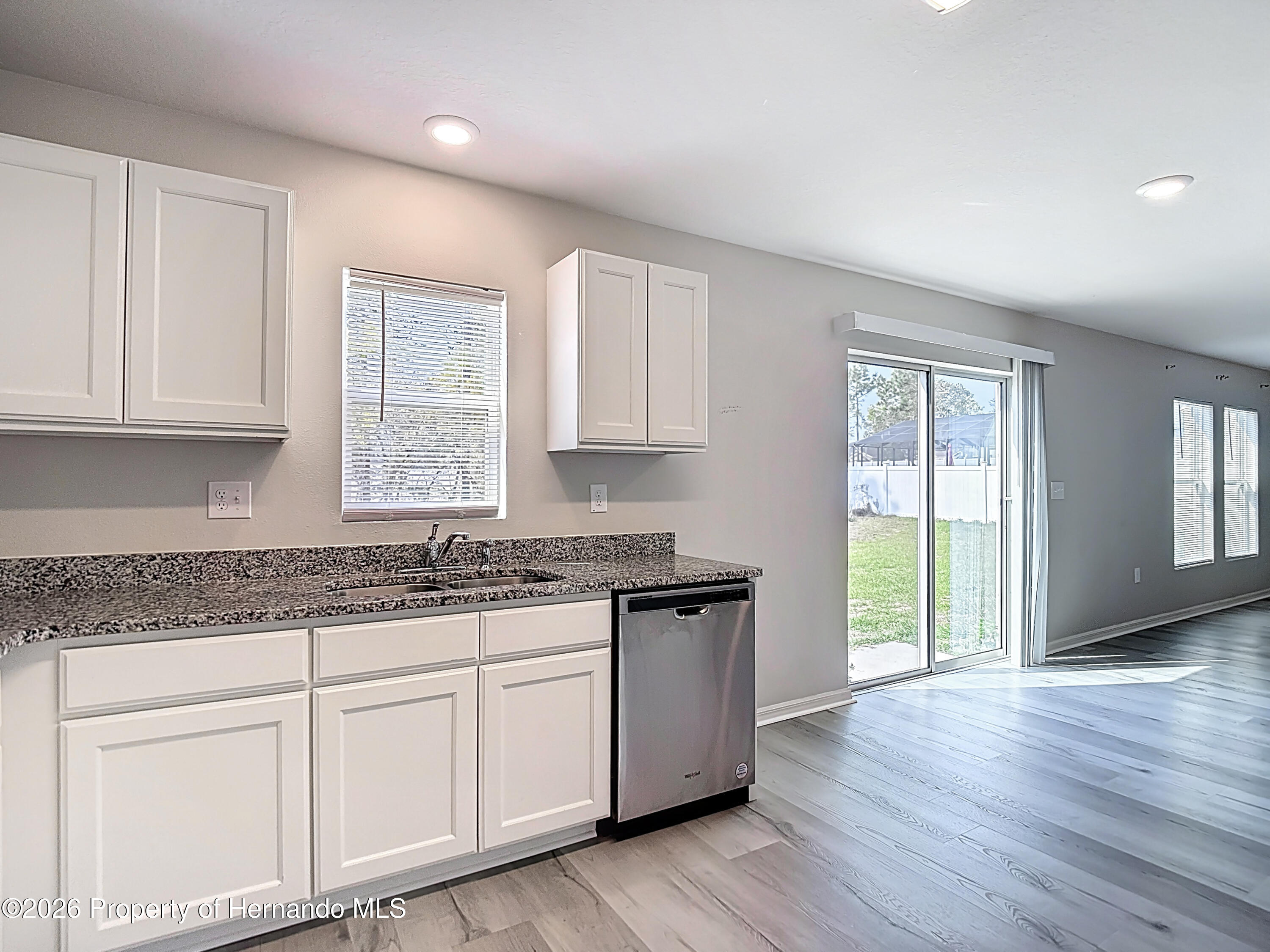 11374 Marcella Avenue Weeki Wachee, FL 34614 - Photo 25 of 70 a kitchen with granite countertop wooden cabinets a sink and dishwasher with wooden floor