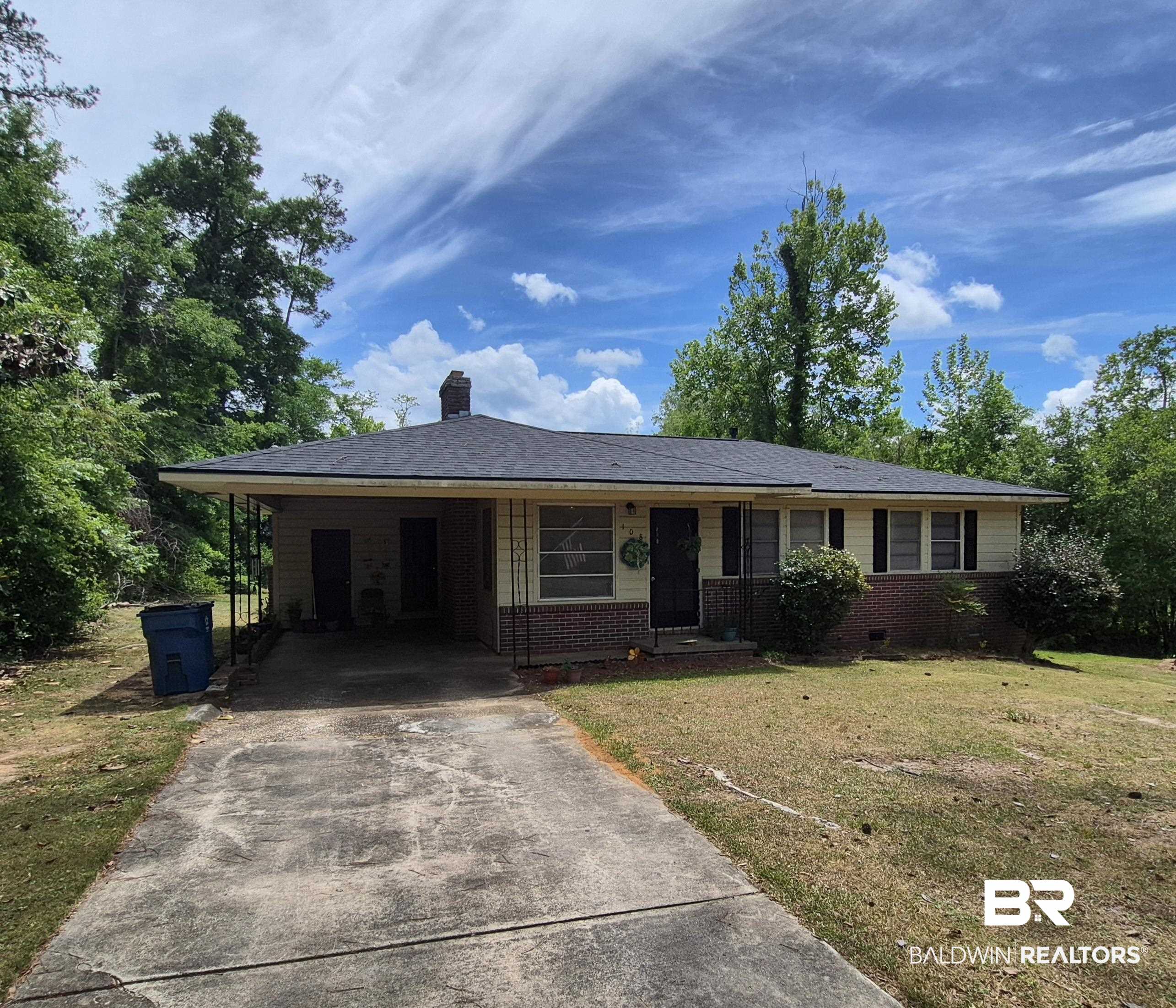 108 Azalea Street Evergreen, AL 36401 - Photo 2 of 19 Ranch-style residence featuring a carport, brick and siding exterior, multi-pane windows, and a mature tree-lined perimeter