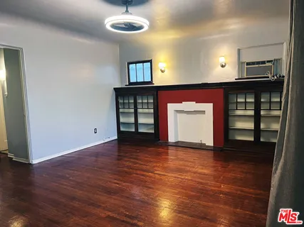 a view of an empty room with a window and wooden floor