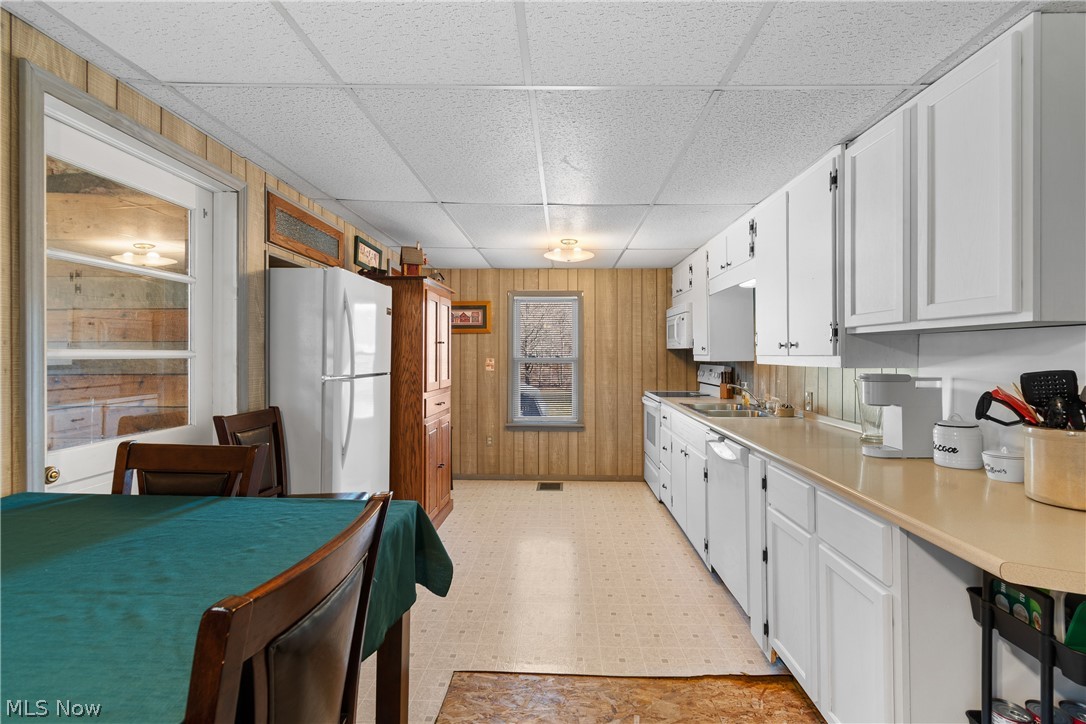 29395 Beitler Road Dennison, OH 44621 - Photo 11 of 33 Kitchen featuring light floors, light countertops, wooden walls, a paneled ceiling, and white appliances