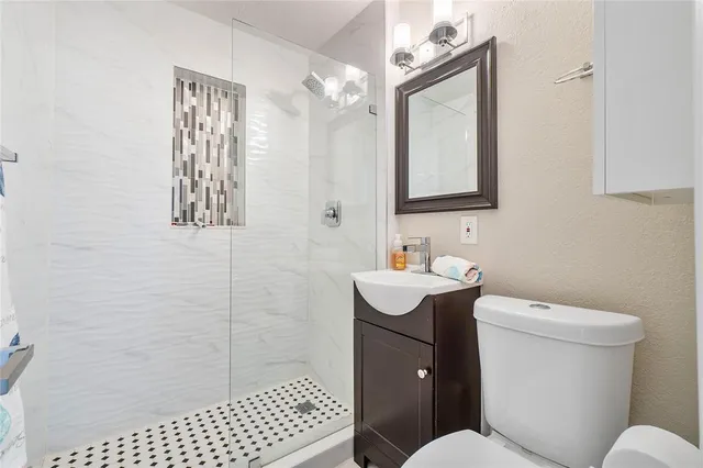 a bathroom with a sink a toilet a mirror and shower