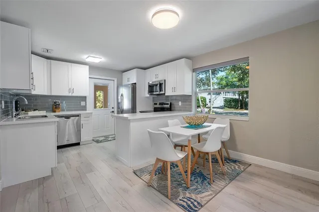 a kitchen with a table chairs a sink dishwasher a stove a microwave oven and a dining table with wooden floor