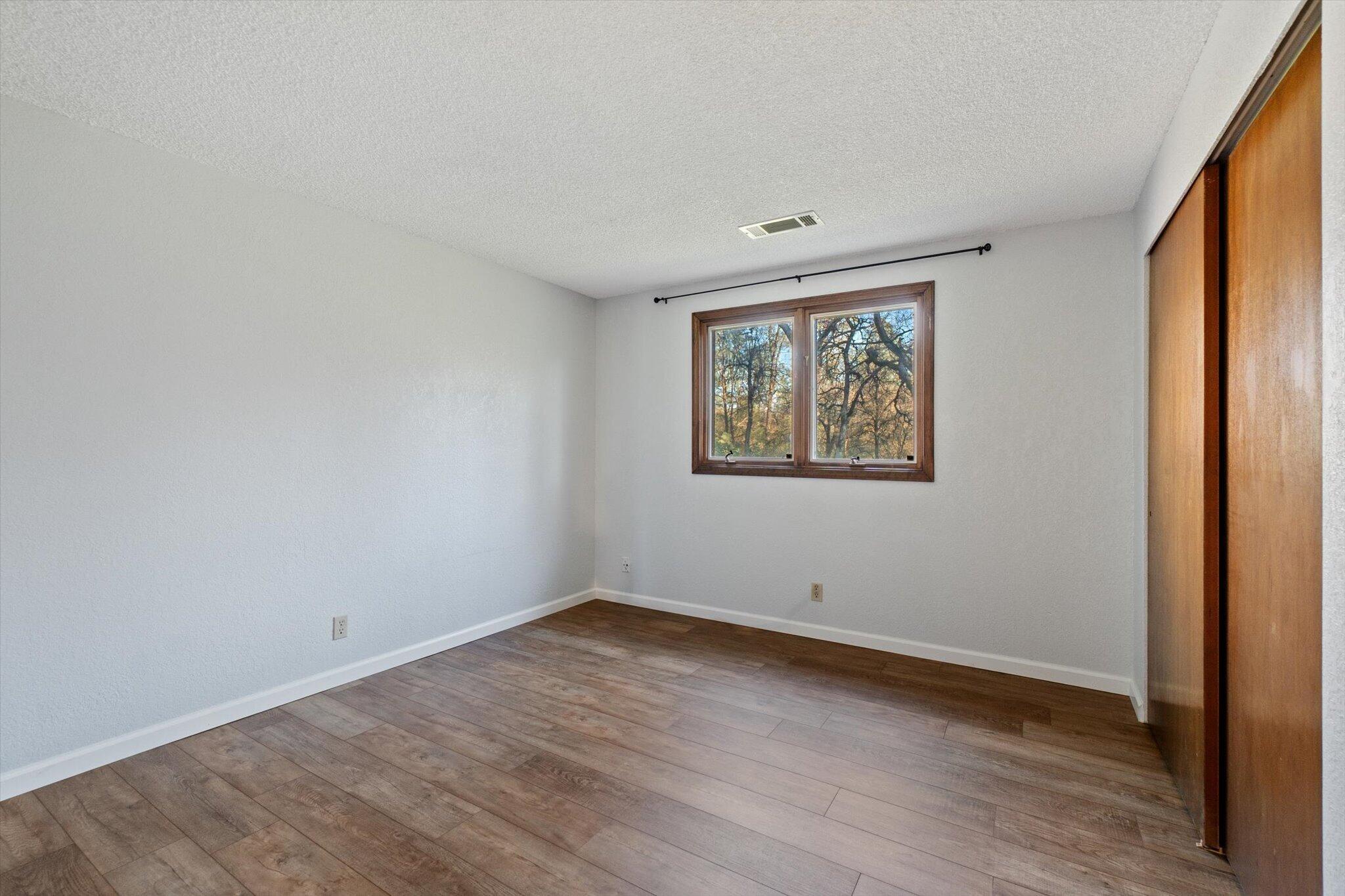 8003 Narrows Way Redding, CA 96001 - Photo 24 of 40 an empty room with wooden floor and window