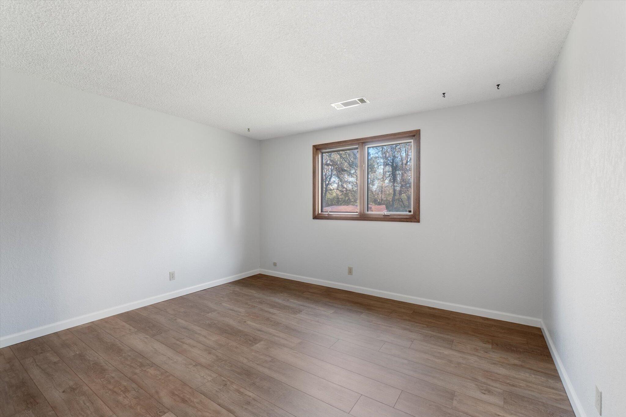 8003 Narrows Way Redding, CA 96001 - Photo 26 of 40 an empty room with wooden floor and window