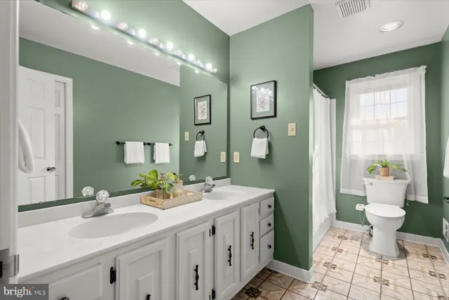 a bathroom with a double vanity sink toilet and a tub