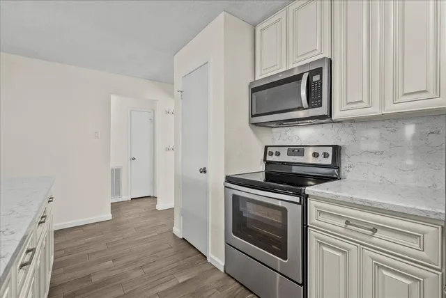 a kitchen with stainless steel appliances white cabinets and a stove top oven